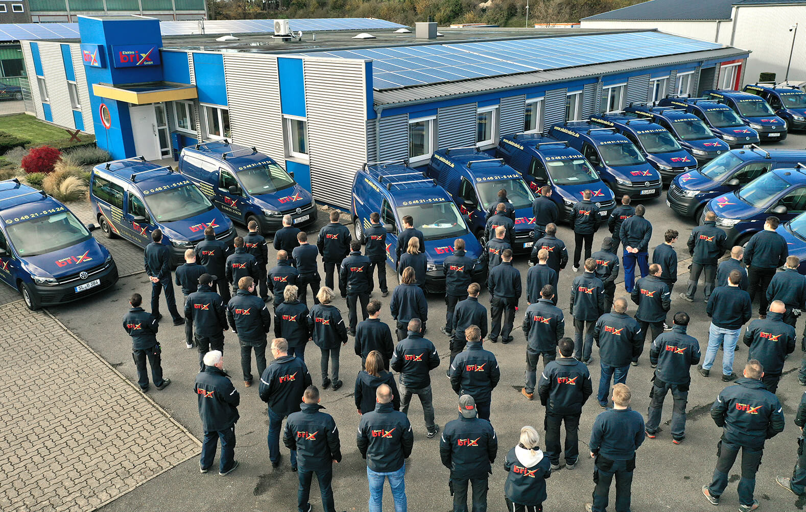 Alle vom Elektro Brix Team auf dem Betriebshof zeigen ihre Jacken mit Brix-Logo