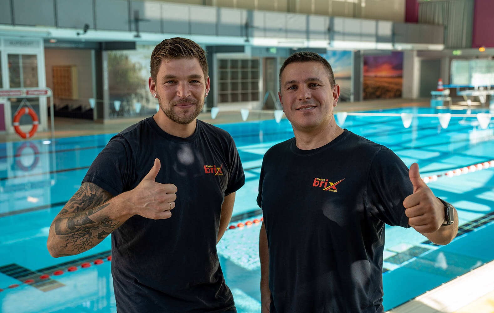Zwei Angestellte von Elektro Brix präsentieren ihre Arbeit in einer Schwimmhalle